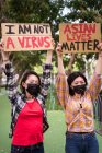 Donne etniche mascherate con manifesti che protestano contro il razzismo in strada e distolgono lo sguardo — Foto stock