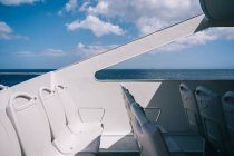 Порожні білі стільці на палубі круїзного човна, що пливе у блакитній морській воді — стокове фото