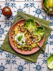 Draufsicht auf appetitanregende Kichererbsen mit Burrata-Käse und verschiedenen Gemüsen und Kräutern, serviert auf dem Teller auf dem Tisch — Stockfoto