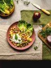 Draufsicht auf appetitanregende Kichererbsen mit Burrata-Käse und verschiedenen Gemüsen und Kräutern, serviert auf dem Teller auf dem Tisch — Stockfoto
