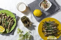 From above of traditional Spanish fried boquerones served on plates with lemons and bowl of white gazpacho soup placed on table with glass of beer in restaurant — Photo de stock