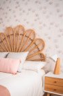 Comodo letto di testiera in rattan vintage naturale carino con cuscini ornamentali in una stanza — Foto stock