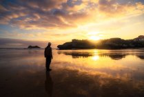 Hombre irreconocible disfrutando de una puesta de sol junto al mar en un día de verano - foto de stock