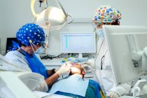 Анонімний стоматолог з колегою в уніформі операційних зубів пацієнта з використанням медичних інструментів у сучасній клініці — стокове фото