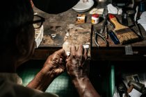 From above crop ethnic craftsman cutting piece of silver with piercing saw in wooden clamps — Stock Photo