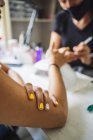 Crop unrecognizable manicurist doing nail art for female client in beauty salon in daylight — Fotografia de Stock