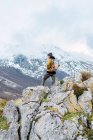 Vista trasera del excursionista con mochila y ropa de abrigo de pie en la cresta rocosa del valle en los picos de Europa y mirando hacia otro lado - foto de stock
