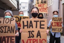 Ativistas étnicos com inscrições I Am Not A Virus e One Race em cartazes durante o movimento Stop Asian Hate na cidade — Fotografia de Stock