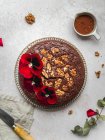 De cima de bolo de chocolate doce decorado com flores vermelhas e nozes servidas na mesa — Fotografia de Stock