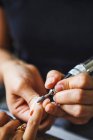 De cima de colheita mestre feminino irreconhecível usando arquivo de unhas elétrica ao fazer manicure para o cliente no salão de beleza — Fotografia de Stock