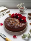 From above of sweet chocolate cake garnished with red flowers and walnuts served on table — Stock Photo