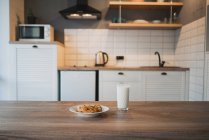 Teller mit leckeren Haferflockenkeksen mit Schokoladenchips gegen Glas Milch auf Holztisch — Stockfoto