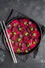 Top view composition of tasty beetroot slices arranged on baking pan with green jalapeno peppers and placed on black towel on kitchen table close to chopsticks — Stock Photo
