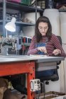 Artesanato feminino focado usando máquina de costura ao criar estofos para assento de moto na oficina — Fotografia de Stock