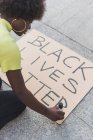 Афроамериканська активістка, що пише чорне життя і робить плакат на знак протесту проти расизму в місті. — стокове фото