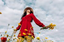 From below of elegant female in hat among blooming flowers in countryside field on summer day — Stock Photo