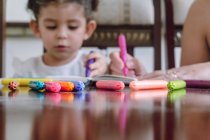 Corte mulher irreconhecível e criança sentada à mesa e desenho com marcadores no caderno — Fotografia de Stock