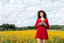 Smiling female in hat taking photo on vintage camera on meadow under cloudy sky — Stock Photo