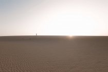 Anônimo turista feminina caminhando enquanto contempla o céu claro com raios de sol ao entardecer — Fotografia de Stock