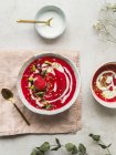 Верхний вид на миску сладкого холодного ягодного супа, украшенную фисташками, подаваемыми на доске для салфеток на столе — стоковое фото