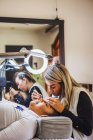 Weibliche Schönheit Meister mit Pinzette Anwendung gefälschte Wimpern auf das Gesicht der ethnischen Kunden im Salon — Stockfoto