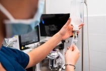 Ernte unkenntlich Tierarzt mit Injektor Füllung Drop-Counter mit Flüssigkeit gegen professionelle Geräte im Krankenhaus — Stockfoto