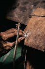 De arriba cosecha artesano étnico corte pieza de plata con sierra de perforación en abrazaderas de madera - foto de stock