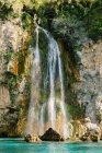 Дивовижний вигляд швидкого каскаду, що падає з грубої скелі в бірюзову лагуну в сонячну літню погоду в Малазі Іспанії. — стокове фото