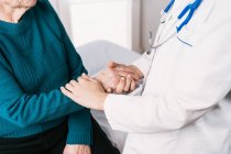 Schnittwunden anonymer Arzt spricht mit älterer Frau während der Untersuchung im Krankenhaus Händchen haltend — Stockfoto