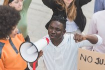 From above African American male screaming in megaphone during Black Lives Matter protest in city while standing in crowd of multiethnic demonstrators — Fotografia de Stock