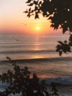 Spettacolare vista del mare calmo increspatura sotto cielo colorato tramonto e sole arancione brillante in Uluwatu — Foto stock