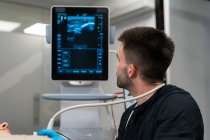 Médico varón revisando el pecho de la mujer en el monitor de la máquina de ultrasonido en el hospital - foto de stock