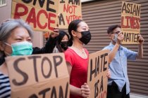 Activistas étnicos con inscripciones de I Am Not A Virus y One Race en pancartas durante el movimiento Stop Asian Hate en la ciudad - foto de stock