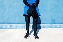 Anonyme gaie femme âgée en vêtements de sport dans des gants de boxe contre le mur bleu — Photo de stock