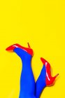 Зверху врожаю невизначена жіноча модель в яскравому взутті та колготках у яскравій студії — стокове фото