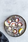 Vista superior fresco vieiras apetitosas en conchas servidas en hielo en el plato con rodajas de limón - foto de stock