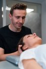 Unshaven maschio fisioterapista massaggio collo della donna con gli occhi chiusi in ospedale — Foto stock