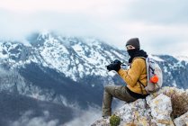 Vista lateral turista femenina con mochila usando cámara fotográfica mientras se dispara increíble naturaleza de Picos de Europa durante el viaje - foto de stock