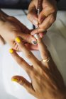 Зверху врожаю невпізнаваний манікюрник займається мистецтвом нігтів для жіночого клієнта в салоні краси в денний час — стокове фото