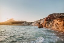 Cenário pitoresco de costa pedregosa áspera lavada acenando mar quente sob céu azul sem nuvens em Fyriplaka Milos em tempo ensolarado — Fotografia de Stock