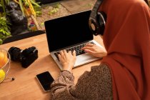 From above anonymous female in headscarf using modern netbook with black screen while sitting at desk — Stock Photo