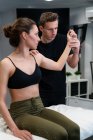 Male physical therapist examining shoulder and arm joint mobility of female patient on bed in hospital — Stock Photo