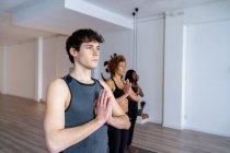 Homme serein en vêtements de sport debout dans la montagne avec des mains de prière pose et faire du yoga pendant les cours en studio — Photo de stock
