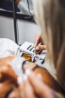 High angle of crop unrecognizable cosmetologist with tweezers applying fake eyelashes for extension on eye of ethnic client in salon — Foto stock