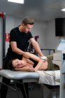 Physiothérapeute masculin appliquant le laser sur la peau dorsale de la femme pendant le traitement médical à l'hôpital — Photo de stock