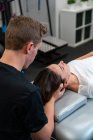 Сверху небритый физиотерапевт-мужчина массирует шею женщины с закрытыми глазами в больнице — стоковое фото