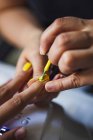 Crop female master applying yellow polish on nails of anonymous client in beauty salon — Fotografia de Stock
