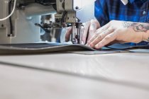 Обрізання чоловічої майстрині за допомогою швейної машини при створенні оббивки для сидіння мотоцикла в майстерні — стокове фото