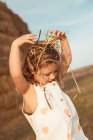 Fröhlich liebenswertes Kind in Overalls spielt mit Heu in der Nähe von Strohballen auf dem Land — Stockfoto