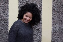 Delighted ethnic female with Afro hairstyle standing on street while look down — Fotografia de Stock